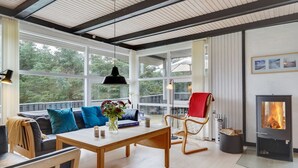 Un salon moderne avec une table en bois, un canapé avec des coussins bleus, un fauteuil à bascule et une cheminée.