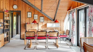 Een gezellig houten interieur met een eethoek, boekenkasten en een groot raam met gordijnen.