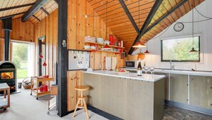 Een gezellige keuken met houten wanden, een centraal eiland en een stenen vloer.
