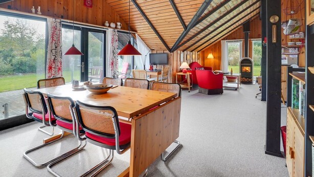 Een ruime eethoek met een houten tafel en stoelen, een open haard en uitzicht op de omgeving.