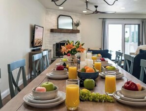 Ein Esstisch, gedeckt mit Früchten, Orangensaftgläsern und einer Vase mit Blumen.