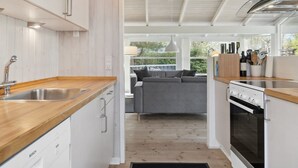 Eine moderne Küche mit weißen Schränken, einem Geschirrspüler von Bosch, Holz Arbeitsplatten und einem großen Fenster mit Blick auf einen Garten.