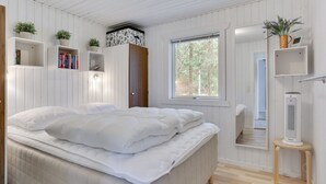 Ein Schlafzimmer mit einem Bett, Einbauschränken mit Büchern, einem Fenster und einer Heizung.
