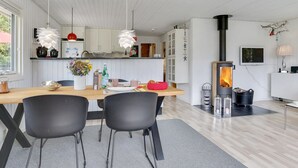 Eine moderne Küche mit weißen Schränken, einer zentralen Kochinsel und einem Kaminofen.