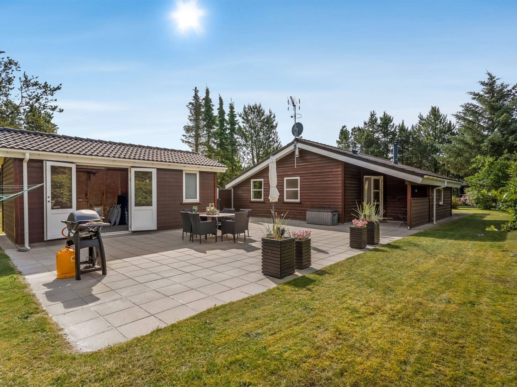 Een huis met twee verdiepingen, een terras, buitenzitplaatsen en een barbecue.