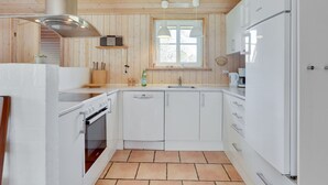 A compact kitchen with white cabinets, a built-in oven, and a window above the sink.