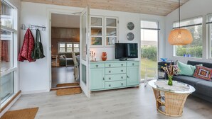 A modern living room with a teal cabinet, a television, and a wicker coffee table.