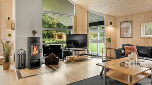 A modern living room with a fireplace, a large TV, and a comfortable seating area. - "Femke" - 250m to the fjord by Interhome (Storvorde)