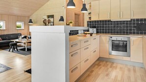 A modern kitchen with wooden cabinets, a black tiled backsplash, and a stainless steel oven. - "Femke" - 250m to the fjord by Interhome (Storvorde)