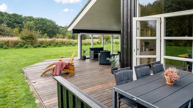 A modern house with a wooden deck, outdoor seating, and large windows. - "Femke" - 250m to the fjord by Interhome (Storvorde)