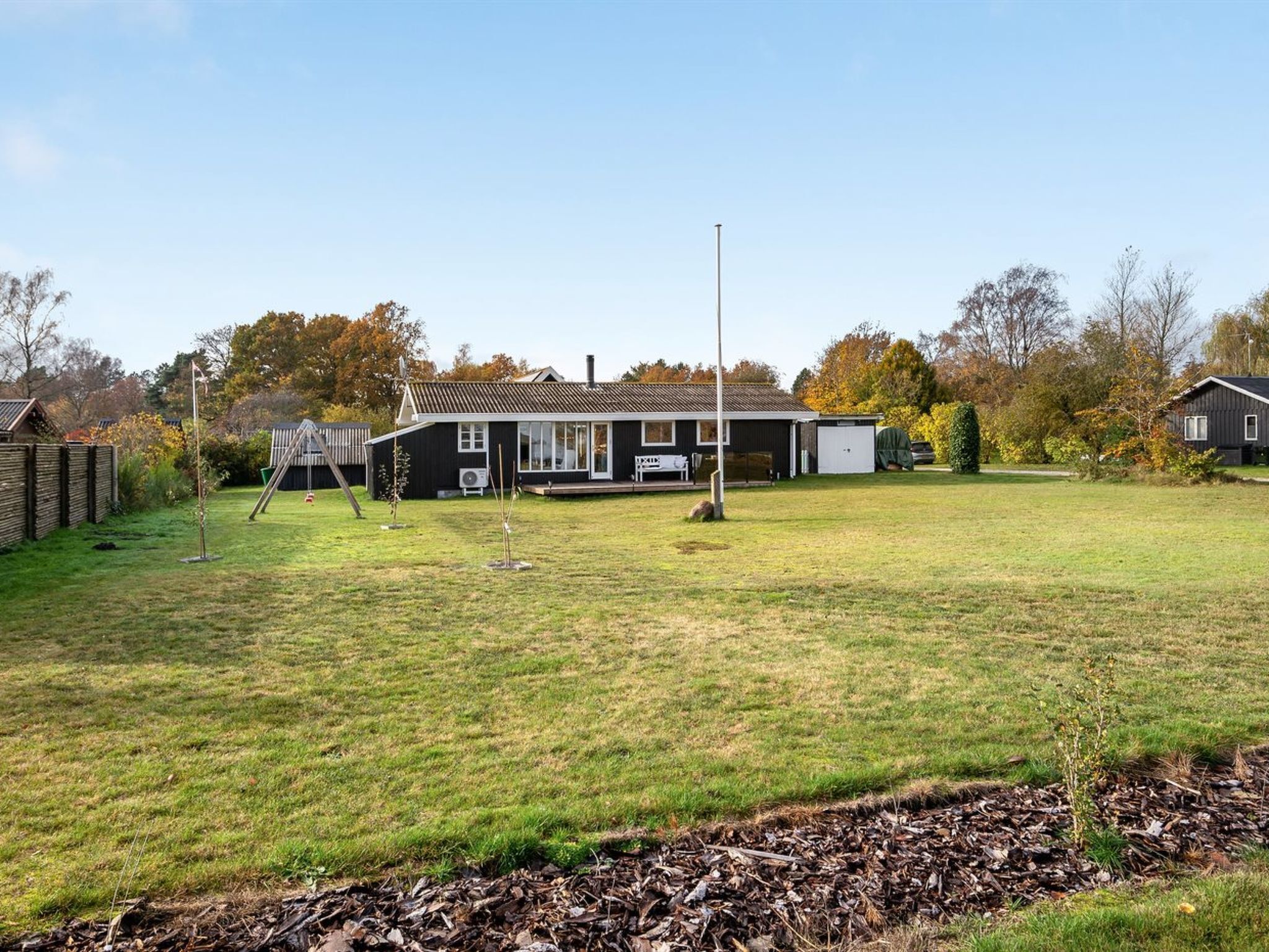 A residential property with a large lawn, a detached house with a sloped roof, and a garage.