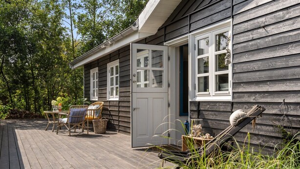 A wooden deck with outdoor furniture, a door, and a window.