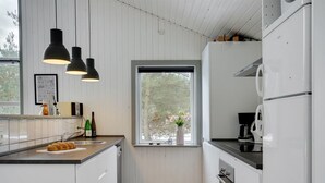 Une cuisine moderne avec des meubles blancs, un plancher en bois et des luminaires suspendus.