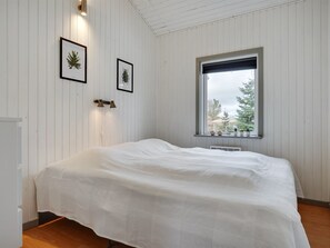 A bedroom with a bed, white walls, a window with a view of trees, and two framed pictures on the wall. - "Aiden" - 300m from the sea by Interhome (Ørsted)