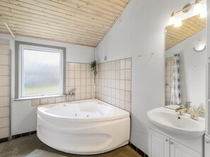A modern bathroom with a freestanding bathtub, a sink, a window, and a mirror. - "Aiden" - 300m from the sea by Interhome (Ørsted)