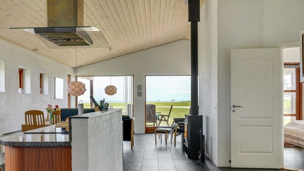 A modern kitchen with a central island, a large stove, and a view of the sea through the open door. - "Roope" - 50m from the sea by Interhome (Storvorde)