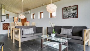 A modern living room with a grey sofa, wooden chairs, a glass coffee table, and pendant lights. - "Roope" - 50m from the sea by Interhome (Storvorde)