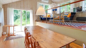 A wooden interior with a dining table and chairs, a sofa, and a TV.