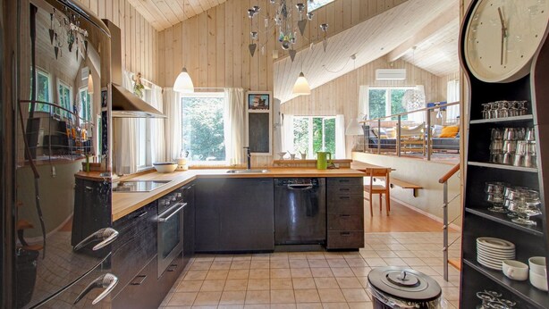 A spacious kitchen with wooden paneling, a central island, and a dining area with a view of the outdoors.