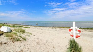 A beach with a lifebuoy sign, a boat, and a sandy shore.
