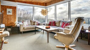 Un salón amplio con un ventanal grande, techo de madera y un conjunto de sofás modernos.