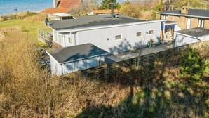 Una casa frente al mar con una amplia terraza, un espacio exterior cubierto y vistas al océano.
