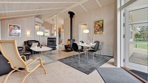 Een ruime woonkamer met een open haard, eettafel en zachte zitplaatsen.
