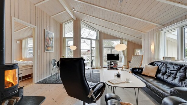 Een moderne woonkamer met een open haard, een leren bank en een eethoek met een televisie en tafel.