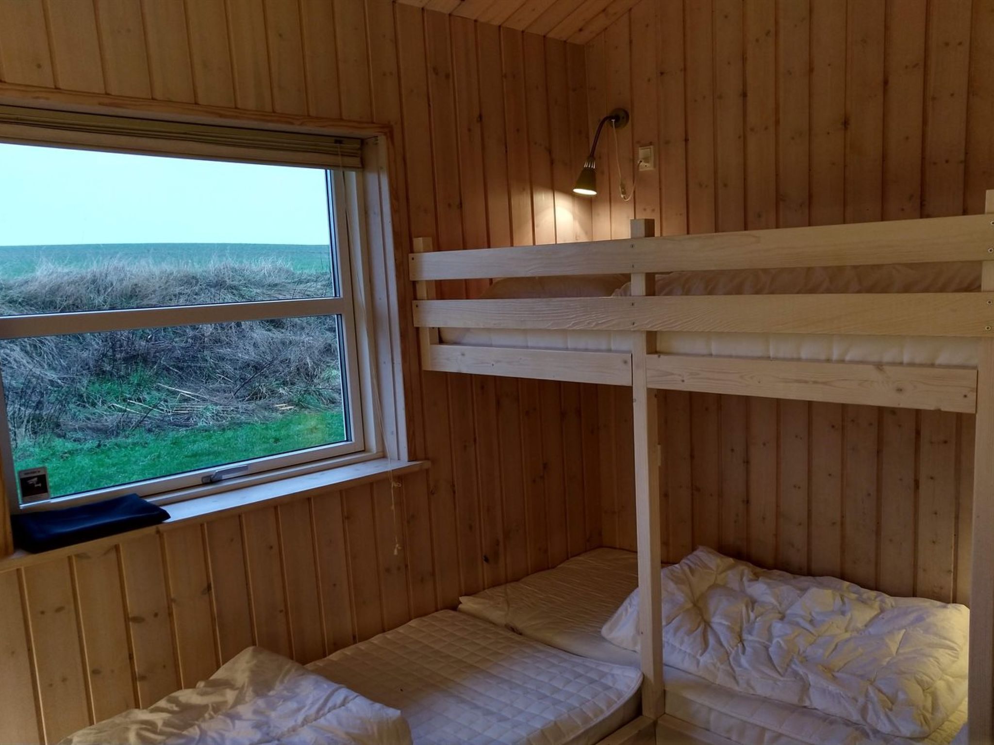 A bunk bed room with a window overlooking a grassy field.