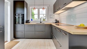Una cucina moderna con mobili grigi, un piano di lavoro in legno e una finestra con vista.