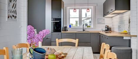 A modern kitchen with grey cabinets, a wooden dining table, and a window with a view.