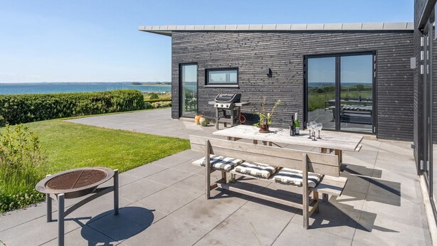 Una casa moderna con patio, una parrilla y vista al mar.