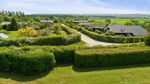 Une propriété rurale comprenant plusieurs maisons, des jardins bien entretenus et une vue dégagée sur la campagne environnante.