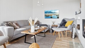 Un salon moderne avec un canapé gris, une table basse en bois, un fauteuil gris et une cheminée.