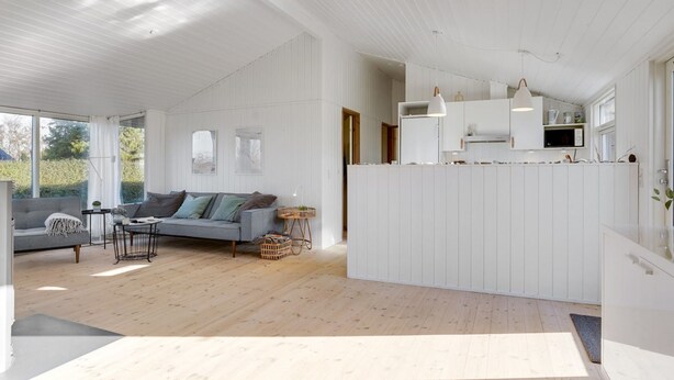 Een modern interieur met een grijze bank, houten vloeren en een keuken met witte kasten.