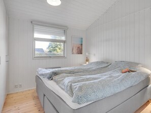 A bedroom with a bed, a window, and a wall-mounted lamp.