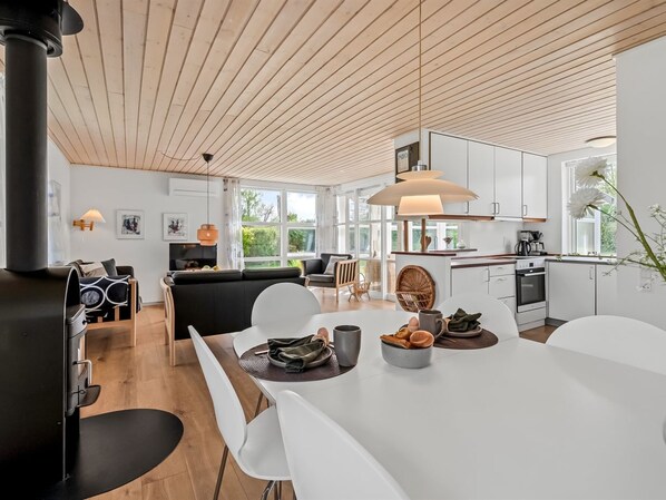A modern kitchen with white cabinets, a large island, and a dining area with white chairs.