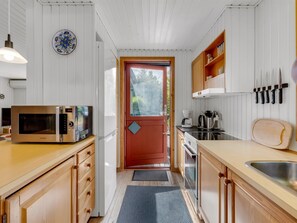 A compact kitchen with wooden cabinets, a microwave, a coffee maker, and a sink.