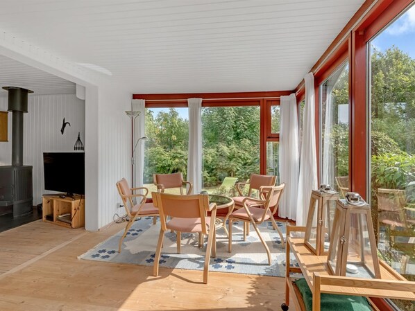 A modern living room with a fireplace, comfortable seating, and large windows offering a view of the outdoors.