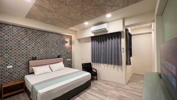 A modern bedroom with a large bed, a headboard, an air conditioning unit, a window with curtains, and a television on a stand.