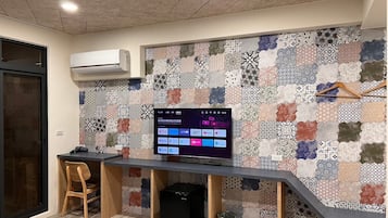 A modern kitchen with a built-in TV, wooden chair, and a patterned backsplash.