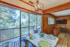 Enjoy meals with a view from this dining area featuring a large table, chandelier, and scenic views of the outdoors.