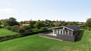 Une maison moderne dotée d’une grande pelouse, d’une antenne parabolique et d’un jardin bien entretenu.
