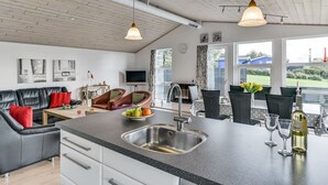 Une cuisine moderne dotée d’un îlot central, d’un évier en acier inoxydable et de luminaires suspendus.