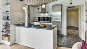 Une cuisine moderne dotée d’un îlot central, d’appareils électroménagers en acier inoxydable et de meubles de cuisine blancs.