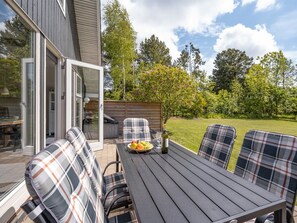 An outdoor patio with a table and chairs, a bottle of wine, and a bowl of fruit. - "Femija" - 500m to the fjord by Interhome (Roslev)