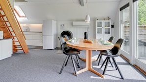 Eine moderne Küche mit weißen Schränken, einer Holztreppe und einem Essbereich mit einem runden Tisch und schwarzen Stühlen.