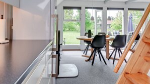 Eine moderne Küche mit großem Fenster, einem Essbereich mit Stühlen und einem hölzernen Stuhl.