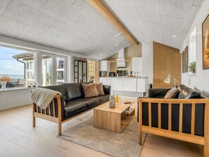 A modern living room with a sofa, coffee table, and a view to the outside.
