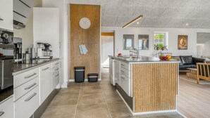 Een moderne keuken met witte kasten, een houten accentmuur en een centraal eiland.